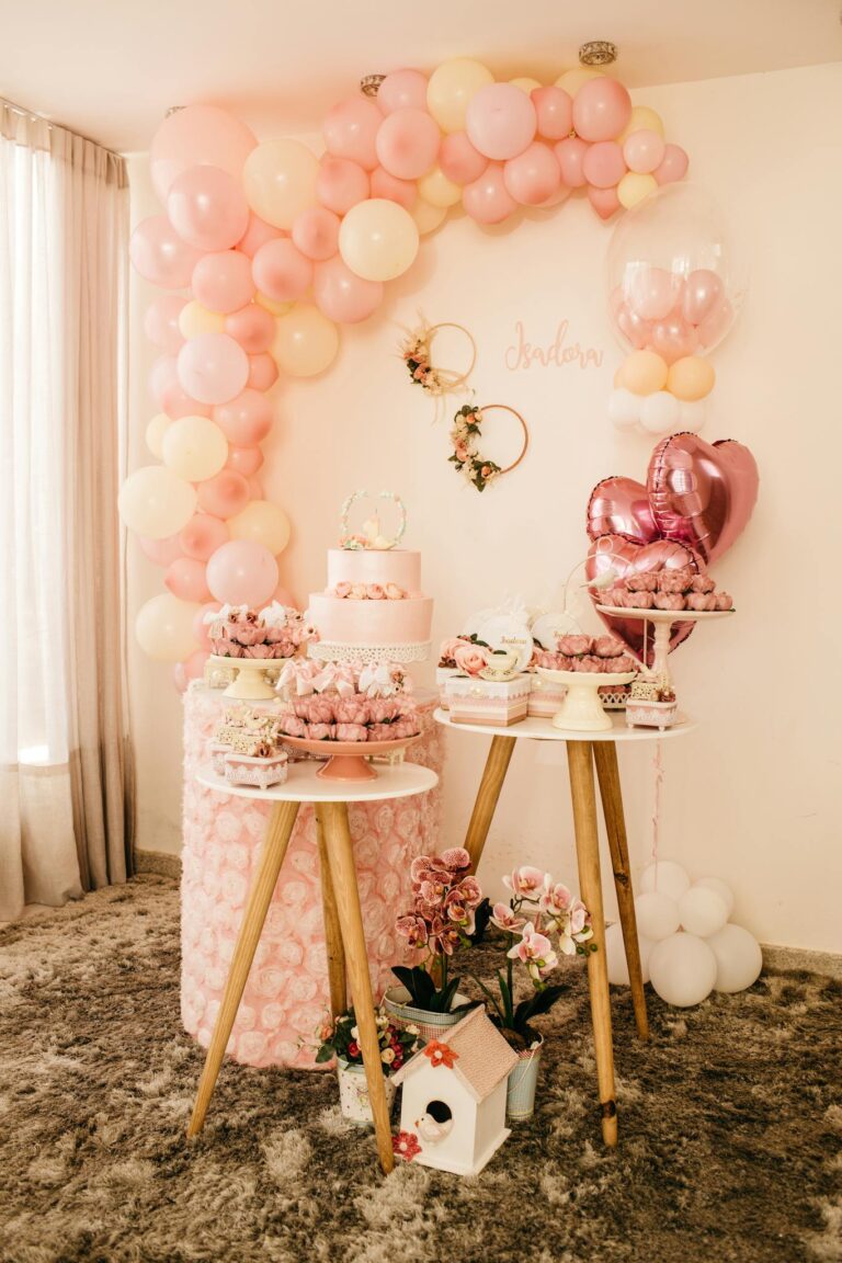 Wedding composition with pink balloons and gentle flowers near decorated cake and desserts